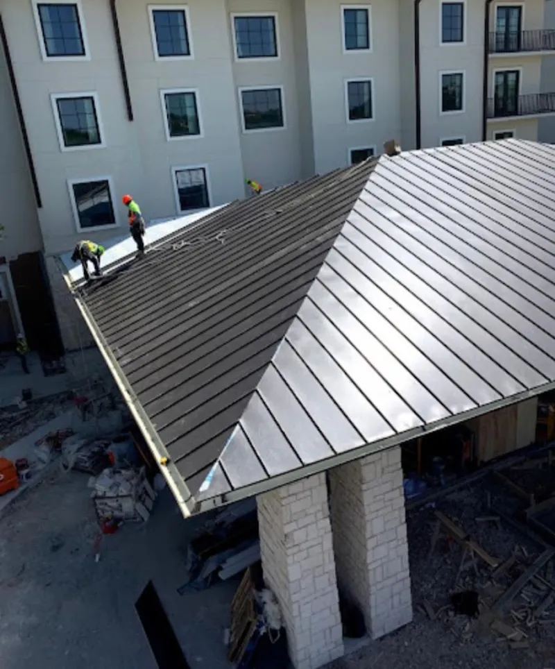 Crew installing standing seam metal roof panels on a commercial project in Connersville